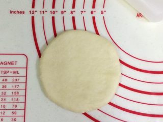 6、香肠玉米奶酪面包,松弛完毕后,把面团擀成圆饼状。