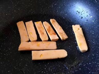 3、早餐 鸡蛋火腿三明治,将火腿肠切成片放入锅中煎至金黄