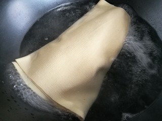 11、豆皮猪皮冻,在肉皮汤冷却的功夫，将豆腐皮整张放入锅里清水煮两分钟。注意别煮破了。