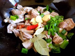 8、牛腩炖土豆,炒干水分后放入葱叶、姜片、红辣椒、八角、香叶、花椒粒翻炒两下。