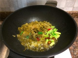 5、酸菜烧鲫鱼,放入酸菜、蒜苗头、泡姜和泡椒翻炒2分钟。