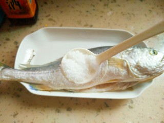 3、清蒸黄花鱼,往切好的鱼里放一勺盐