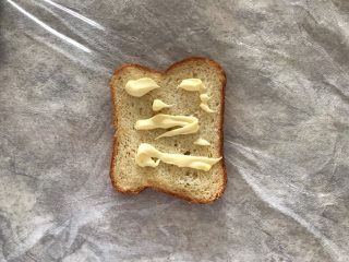 6、巨无霸口袋三明治,放一片吐司在保鲜膜中间位置，并挤上适量沙拉酱