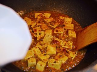 21、正宗地道的麻婆豆腐,煮到还剩少量汤汁时，倒入水淀粉。用铲子轻推。
