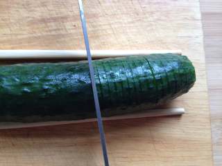 3、蓑衣黄瓜,刀与黄瓜成直角，均匀切成2mm左右连刀片（注意，黄瓜头比较细，筷子不够高，切的时候要悠着点，别切断了）