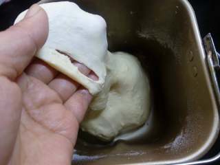 2、肉松面包卷,打至能拉出厚膜的状态，注意调整好面团的干湿度，面粉的吸水率和季节不同，预留总水量的10%左右，视面团的状况来加。