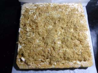 13、肉松面包卷,一定要趁热来卷哦。面包倒扣的油纸上，也能更好的把面包卷起，在靠近自己身体的一侧，相隔1厘米左右，浅浅横切二刀，注意不要把面包切断。在离自己较远的那一端，以45度角斜切一刀，这样卷起切片后会比较美观，不切也可以的。在面包的反面涂上一层沙拉酱，撒上肉松。