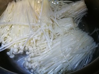 2、酸汤肥牛,锅中水开倒入洗净的金针菇 煮开后捞出