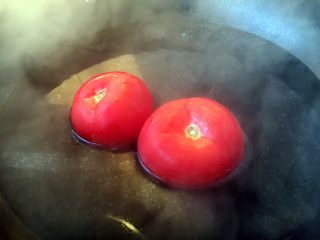 2、番茄鸡蛋青豆,在番茄的顶部划一个十字口，放在开水里焯烫一下，然后去皮。