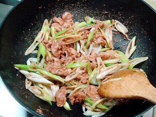 11、腐乳爆肉,然后烹入碗汁用旺火炒匀,炒匀后倒入葱丝。