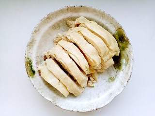 10、口水鸡,将冰镇好鸡腿切成块,码放在盘中。