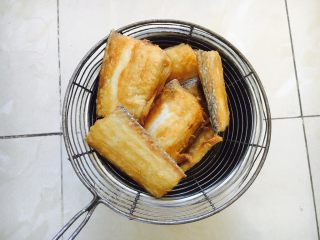 6、红烧带鱼,煎好的鱼放在笊篱里沥油。