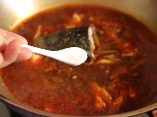 9、麻辣水煮鱼,加入鱼头、鱼骨翻炒片刻。倒入刚才焯蔬菜的水，和鱼头、鱼骨一起炖煮5分钟。期间调入一汤匙生抽、一汤匙料酒、一茶匙盐、一茶是糖、一汤匙醋调味。