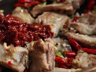 9、川香土豆炖排骨,放入干红辣椒翻炒出香味,接着加入郫县豆瓣酱炒出红油。