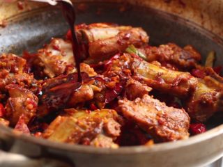 10、川香土豆炖排骨,淋入料酒、生抽翻炒均匀。