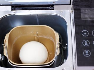 3、百吃不厌的韭菜盒子,和好的面团用手揉圆后放入面包桶里静置一会。