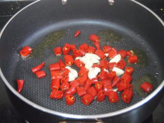 10、辣子鸡, 热锅，倒入适量的金龙鱼外婆乡小榨菜籽油，爆香蒜末后放入湿辣椒炒至表皮起泡