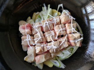 9、东坡肉,然后把捆扎好的五花肉皮朝下整齐的码在葱、姜上。