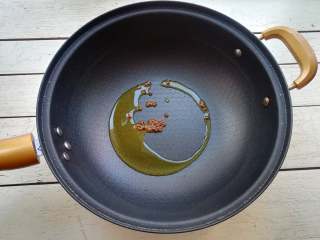 8、干煸花菜,锅内再添加少许油,下入花椒,小火炒制花椒变得微焦,将花椒捞出不用