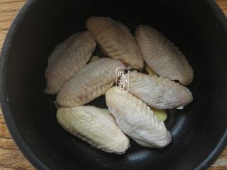 6、简单方便的电饭煲可乐鸡翅,放进鸡翅，鸡翅皮朝上，姜片要放在鸡翅底下，这样去腥，防止粘锅。