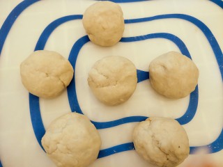 5、香蕉牛奶椰蓉包,排气以后分成六个小面团，盖保鲜膜静置15分钟。面团会有点黑，是加了香蕉的原因。