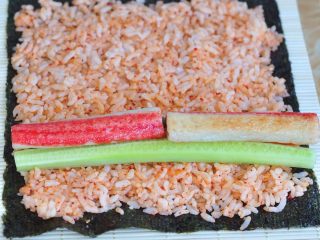 4、韩式紫菜包饭便当,摆上蟹棒、胡萝卜条、黄瓜条、煮熟的四季豆。