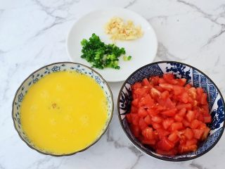 2、番茄鸡蛋拌面,番茄洗净在顶部切十字，放入开水中烫一分钟取出去皮，再切成小块，鸡蛋打散备用，蒜切末，葱切葱花