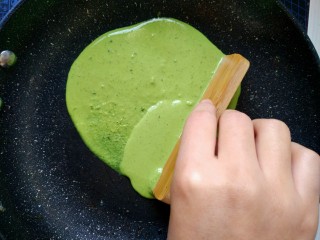 8、菠菜煎饼果子,用小竹片，或者铲子，刮匀。面糊流动性很强直接转锅也是可以的.