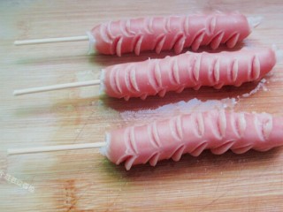 8、脆皮孜然香肠,把竹签插在香肠上，准备煎炸