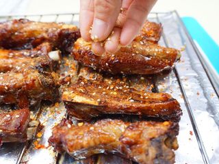 13、蜜汁烤排骨,再撒一层辣椒粉、孜然粉和白芝麻,放入烤箱继续烤。