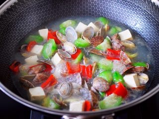 13、丝瓜花蛤炖豆腐,加入红椒丝,大火继续煮沸。