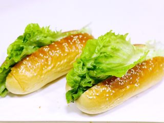 14、热狗面包,待面包放凉后,用锯齿刀在面包中间切一刀,不要切断,铺上生菜叶。