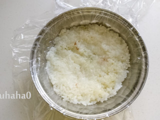 6、糯米红豆糕,用一个碗或其他喜欢的容器，在容器里铺一层保鲜膜，在碗底铺一层放凉的糯米饭，用手压实。