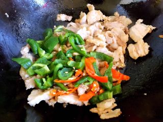 7、炒五花肉,放入青椒和红辣椒块。