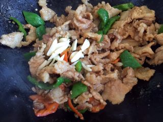 10、炒五花肉,放入蒜片翻炒均匀。