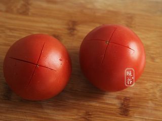 2、酸爽下饭的茄汁土豆丝,先把番茄底部划十字;