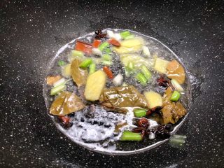 5、萝卜烧牛腩,锅里放入适量油，先把葱白和姜片放入炒出香味，再把八角、桂皮、香叶放入炒香。