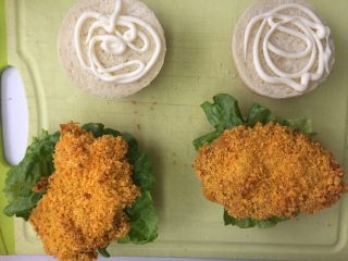 15、劲脆汉堡包,汉堡胚切成两半，在底部汉堡胚上挤上沙拉酱，放入生菜叶，再加上烤好的鸡腿块和猪排，再放上一片芝士片，再放上一片汉堡胚