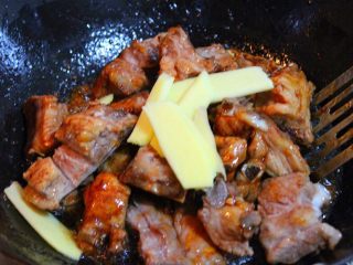 5、红烧排骨,将排骨倒入锅中，转中火，快速翻炒，让排骨均匀裹上糖色，放入姜片继续翻炒，倒适量酱油炒匀。