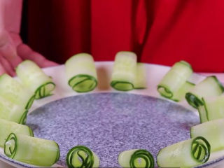 10、家常红烧肉的正确做法,做法简单又香又美味,趁着焖肉的功夫,我们开始来准备摆盘,取一小节的青瓜,用刮皮刀削成薄片后,卷成青瓜卷,绕着盘子摆一圈后备用。