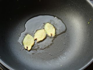 8、照烧鸡腿,炒锅放一点点油,放入姜片,煎炒一会,姜片表面变抽抽,并且能闻到姜味。