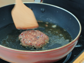 5、牛肉汉堡,平底锅倒入调和油，油烧到七成热，把肉饼放入炸至焦黄。可以轻轻用锅铲压一压肉饼，让饼的形状更牢固，不容易散开。