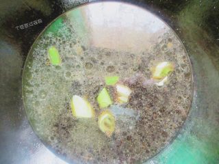 6、面筋塞肉,煮过里上入少许清水,加入一些葱花、生抽,老抽和糖,烧开