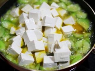 8、鲜掉眉毛的丝瓜豆腐汤,把沥干水的豆腐捞出放入锅中。