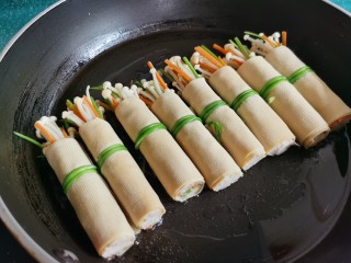 12、豆皮金针菇卷,锅放油烧热,放入豆皮卷煎一下。