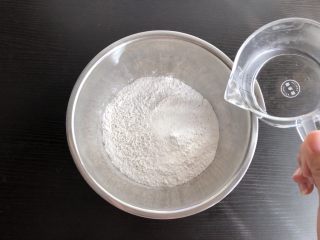2、老北京驴打滚,加入温开水，边加入边用筷子搅拌成絮状