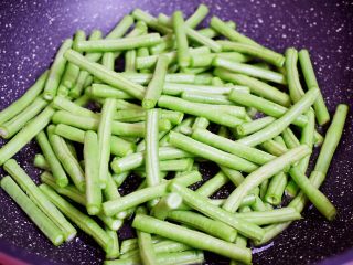 3、干煸豆角,锅中倒入适量的食用油烧热，放入豆角炸至表面起皱