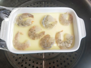 11、虾仁蒸蛋,15分钟后,鸡蛋液已经凝固,揭开保鲜膜,把虾仁摆放在表面,再盖上保鲜膜,继续蒸五分钟。