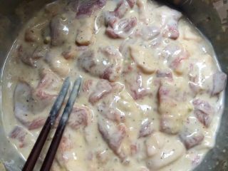 6、正宗小酥肉,把腌制好的肉加入到粉浆里，用筷子搅拌均匀。