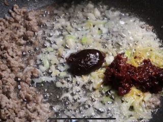 4、麻辣鲜香的麻婆豆腐,热锅烧油至七成热,下肉糜炒酥,撇到一边,下葱姜蒜末炒香,下郫县豆瓣、甜面酱炒香,再次与肉糜翻炒均匀